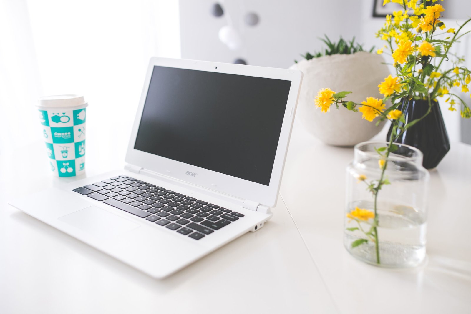 A laptop and a to-go coffee cup on a desk, ready for writing a review